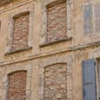 Façade d'un immeuble ancien avec des fenêtres murées et une fausse fenêtre peinte en trompe-l'œil