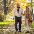 Un couple de seniors marche d'un bon pas dans un parc
