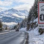 Panneau d'entrée dans une zone où les équipements hivernaux sont obligatoires, au bord d'une route de montagne enneigée
