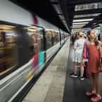 Des voyageurs sur un quai où passe le RER