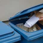 Femme jetant les déchets de papier dans le conteneur bleu spécial 