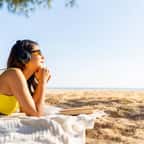 Jeune fille écoutant de la musique à la plage