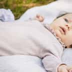 Un b&eacute;b&eacute; allong&eacute; sur une couverture pos&eacute;e sur l'herbe