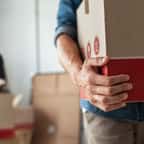 Un homme porte un carton de déménagement