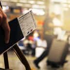 un homme tient son billet d'avion et sa valise