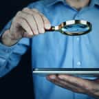 Un homme tient une loupe et une tablette