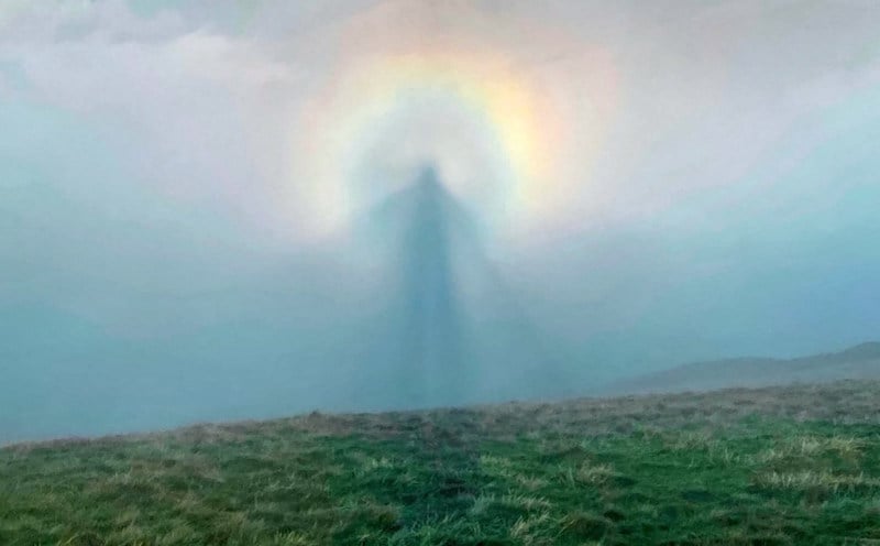 Un randonneur photographie une silhouette angélique dans le ciel entouré d'une auréole arc-en-ciel PRI_137249117