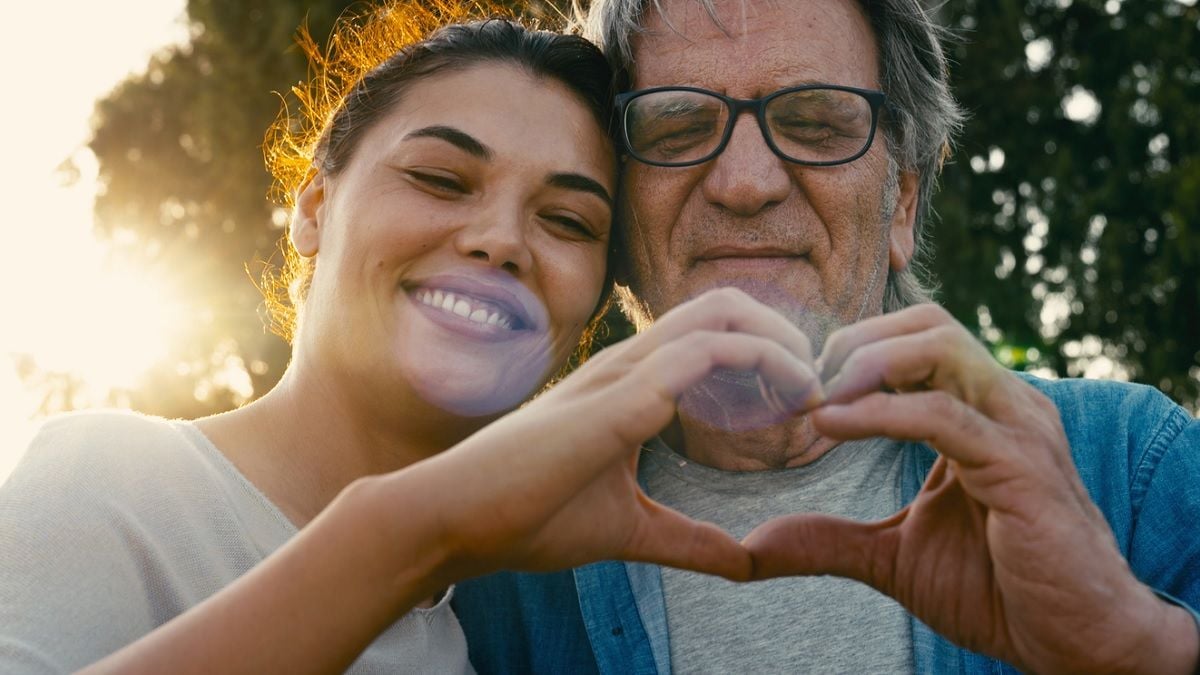 Couple avec une différence d'âge faisant un coeur avec leur main