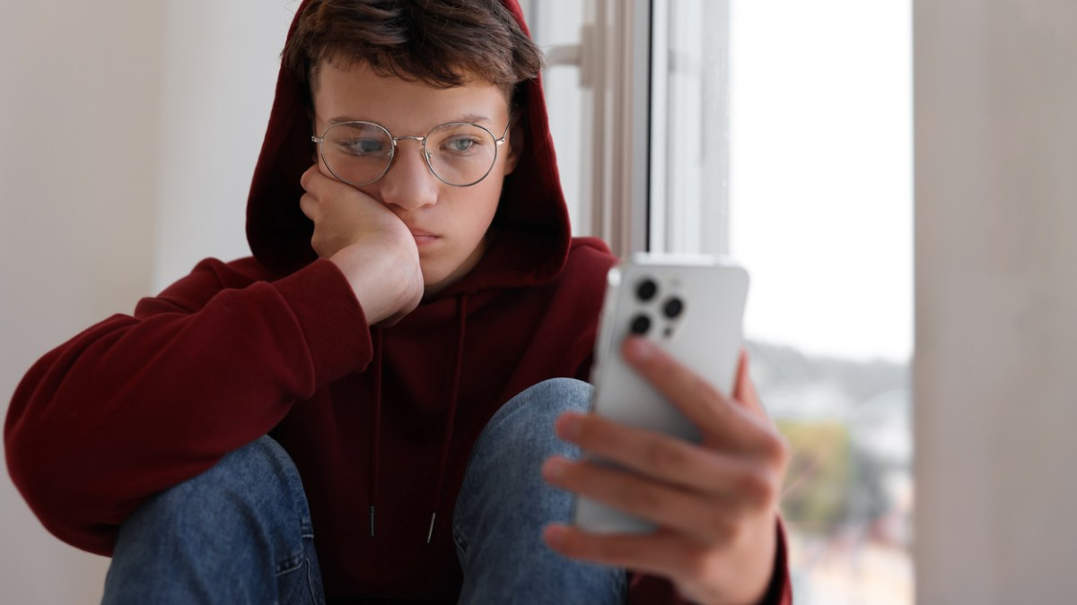 Un jeune inquiet devant son téléphone