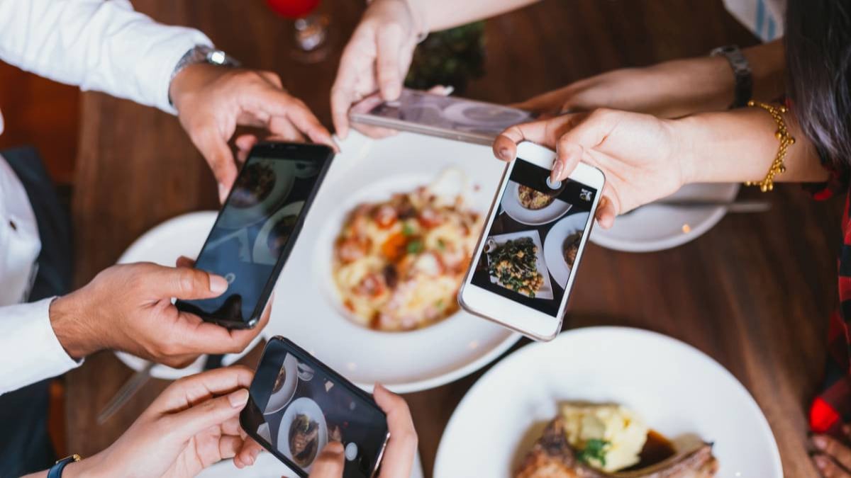 Groupe d'amis prenant en photo leur plat avec leur smartphone