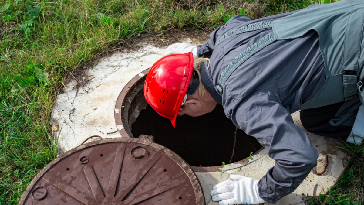 un agent d'entretien relève une fosse septique