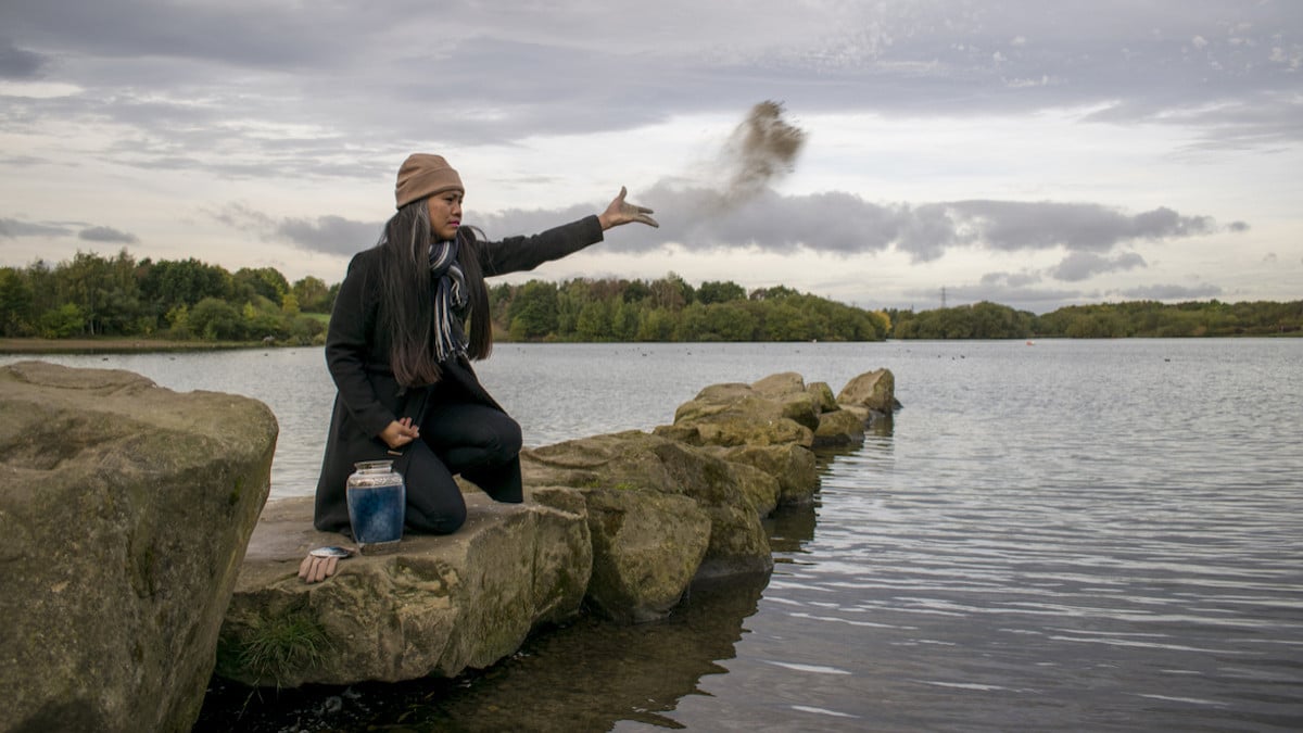 Une femme qui disperse des cendres dans un lac 