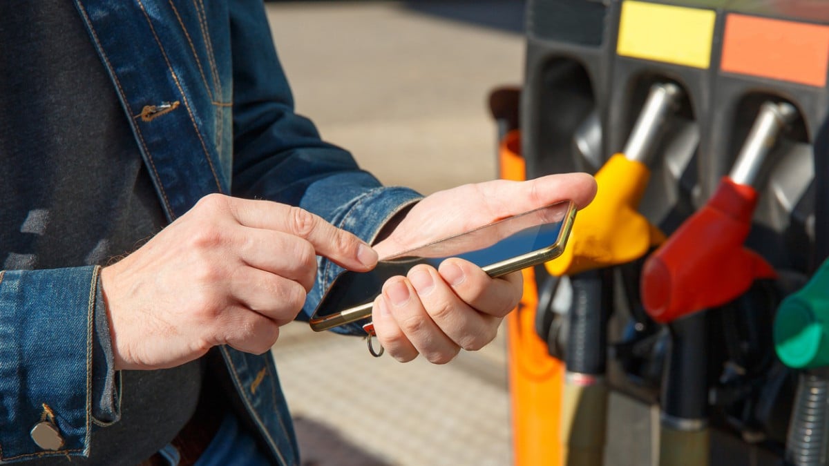 Une personne utilise son smartphone à la station-service