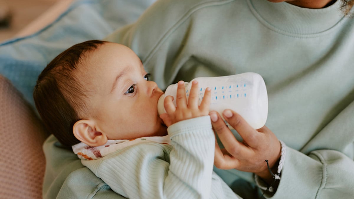 Un bébé boit son biberon