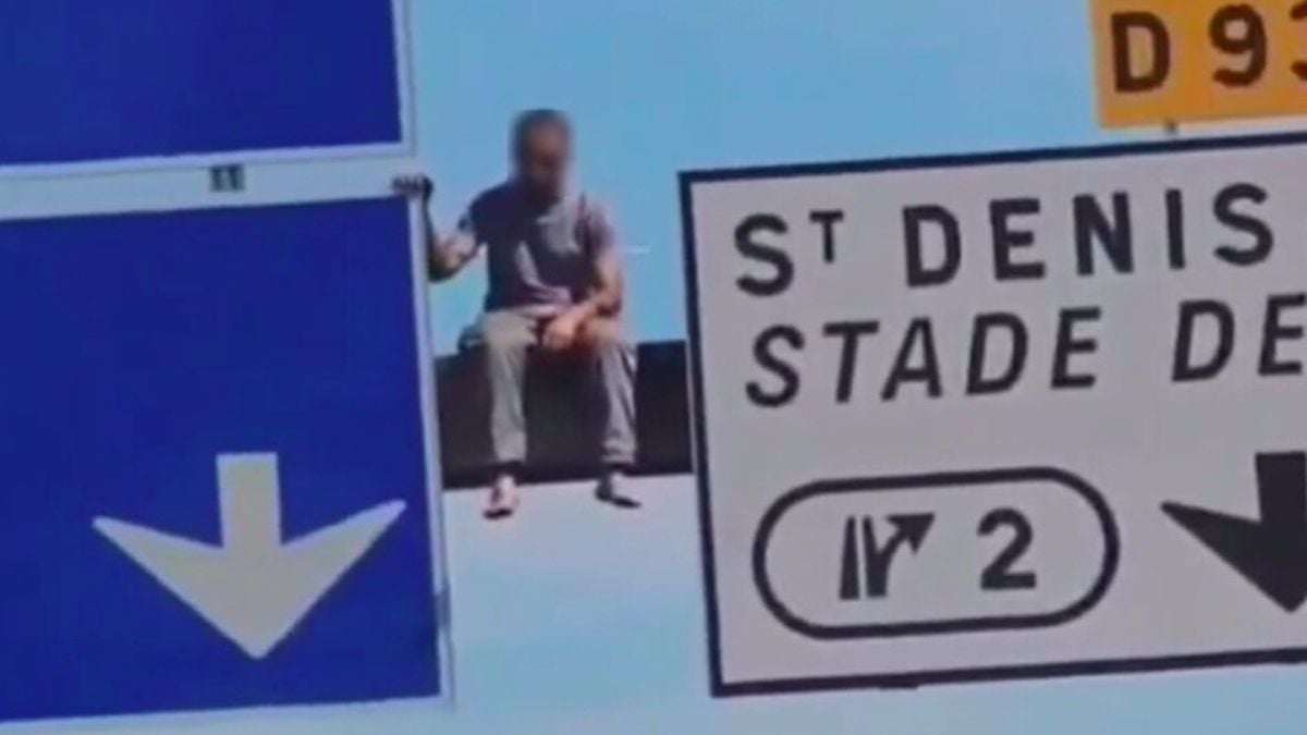 Un homme perché sur un panneau de l'autoroute A1, en région parisienne 