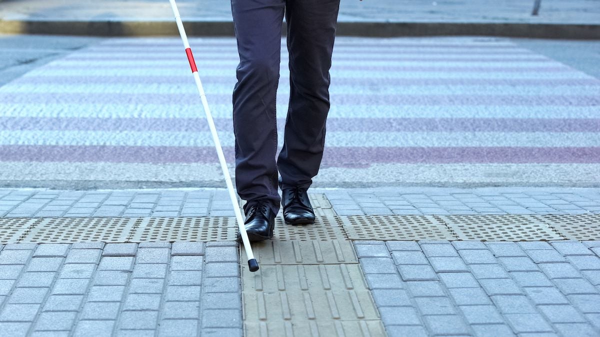 Une personne aveugle utilisant une canne pour marcher dans la rue 