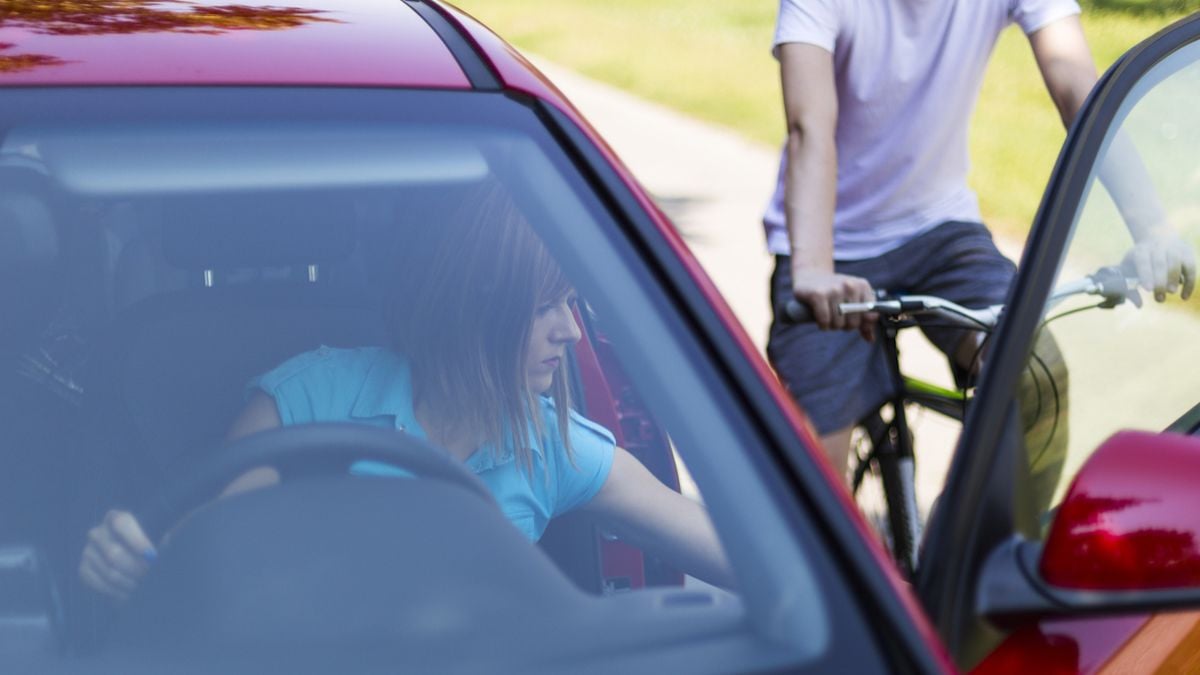 Une automobiliste en train d'ouvrir sa portière de voiture alors qu'un cycliste s'approche 