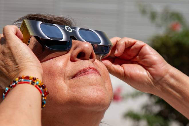 Femme &acirc;g&eacute;e regardant l'&eacute;clipse solaire avec une paire de lunettes