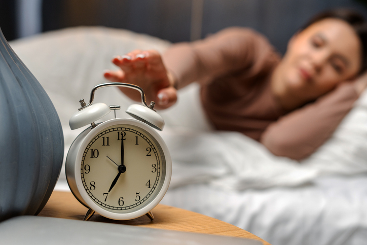 Une femme règle son réveil dans son lit