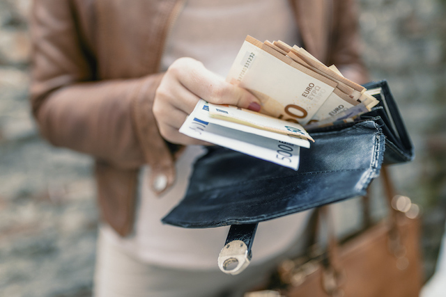 Une femme qui sort des billets de 50 euros de son portefeuille