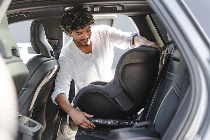 Un homme installe un siège auto dans une voiture