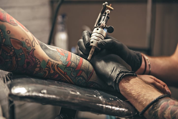 Un tatoueur tatoue une personne