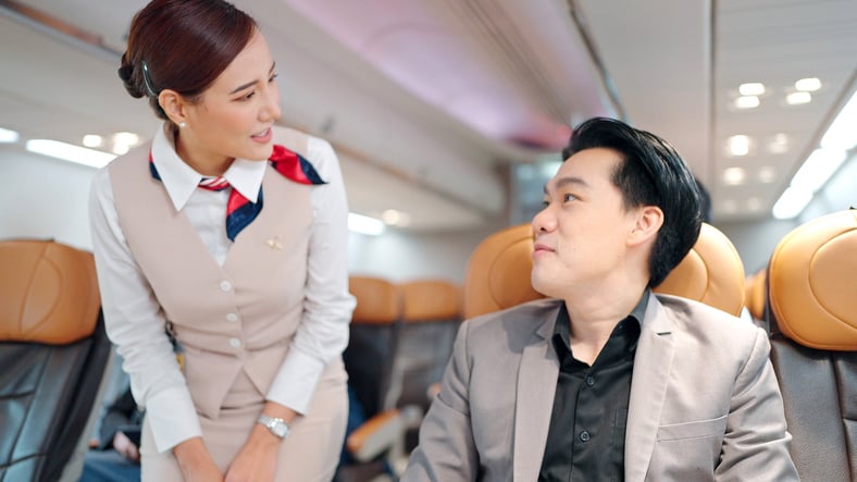 Une hôtesse de l'air parle à un passager dans l'avion