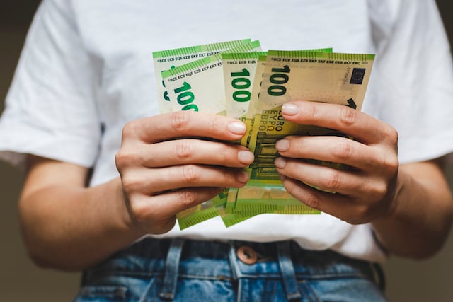Une femme qui tient une liasse de billets de 100 euros