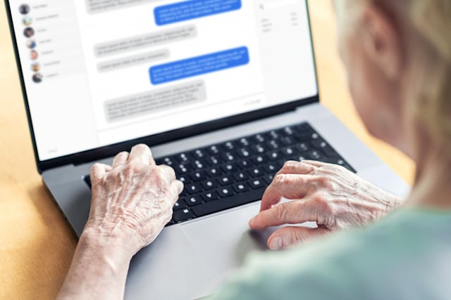 Une femme âgée en train d'envoyer un message via son ordinateur