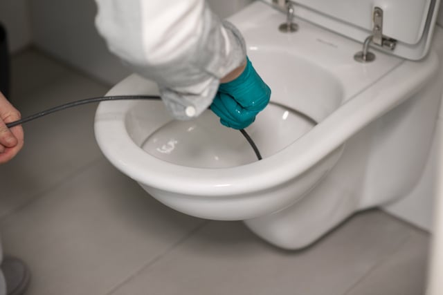 Un plombier qui utilise un furet pour déboucher WC