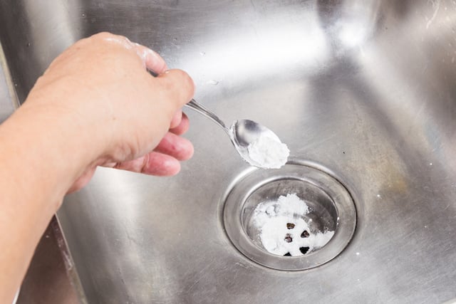 Une femme verse une cuillère de bicarbonate de soude