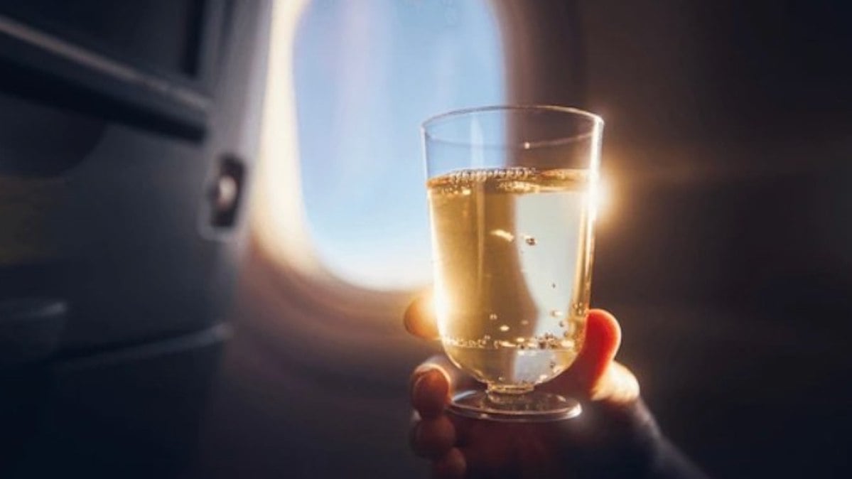 Un passager qui tient un verre de vin blanc