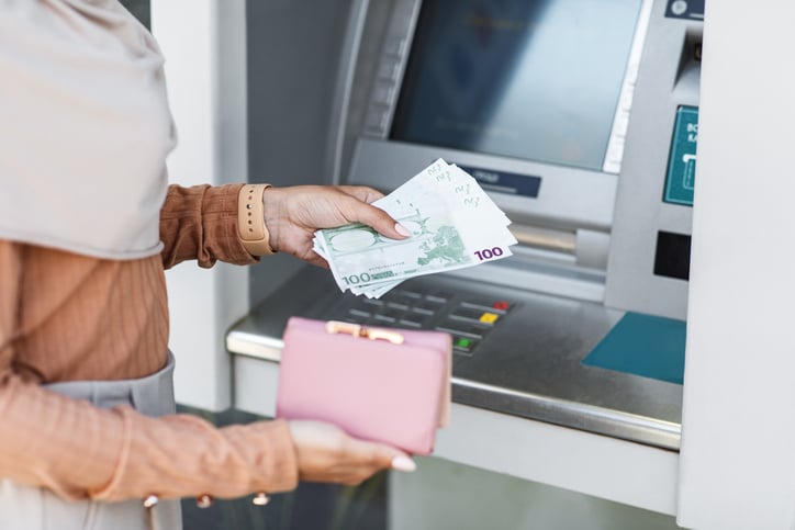 Une personne retire beaucoup d'argent dans un distributeur de billets