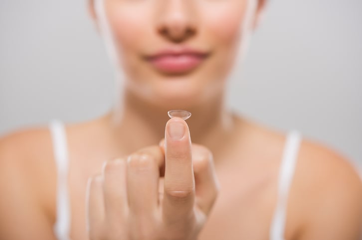 Une femme tient une lentille de contact