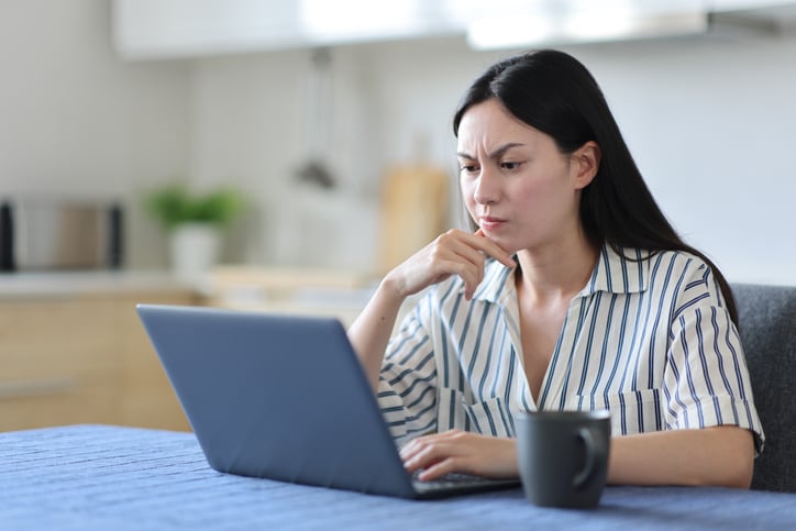 Une femme réfléchit devant son ordinateur