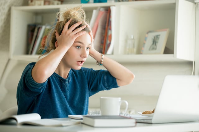 Une femme a l'air choqué qui regarde son ordinateur 