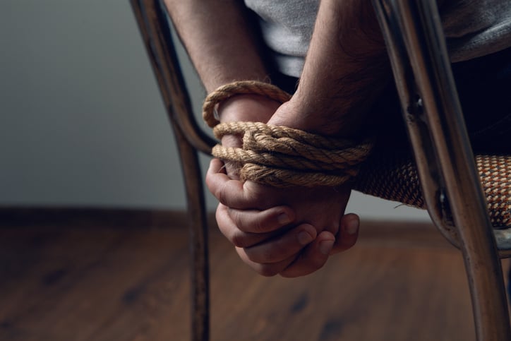 Un homme ligoté sur une chaise