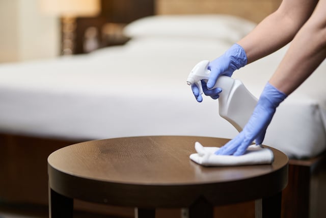 Une femme de ménage qui nettoie une table dans une chambre d'hôtel