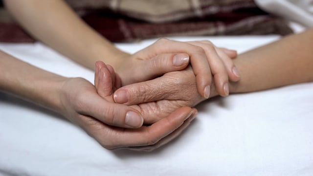 Une femme âgée et sa fille se tiennent la main 