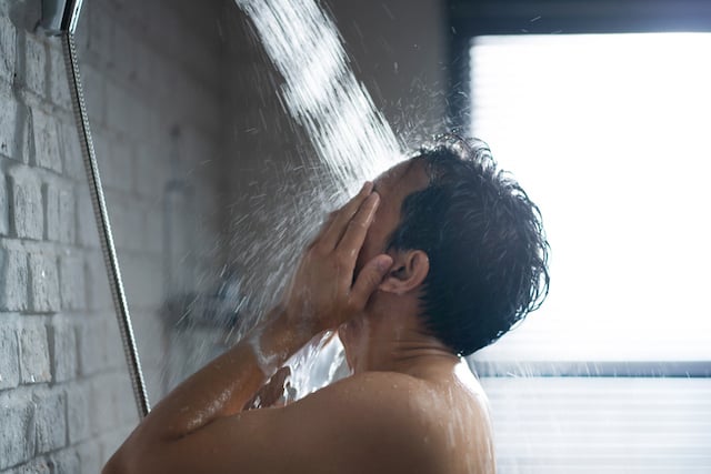 Un homme qui se rince la visage sous la douche