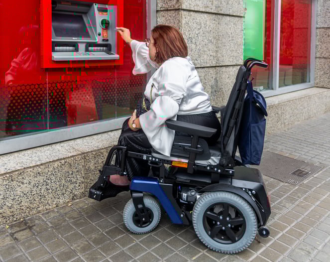 Une personne handicapée retire des espèces dans un distributeur de billets