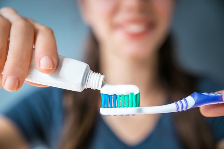 Une femme met du dentifrice sur une brosse à dents