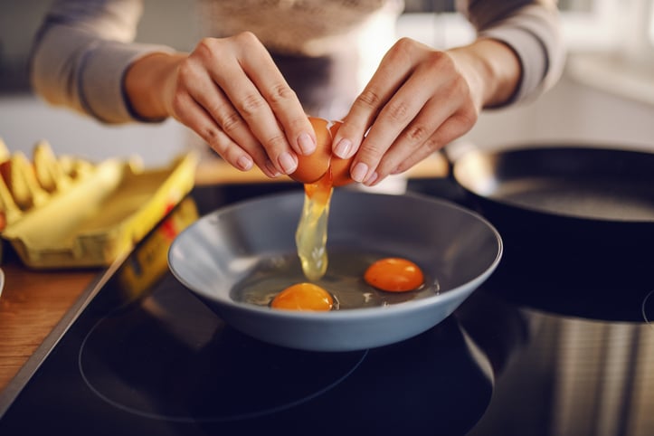 Une femme casse des oeufs