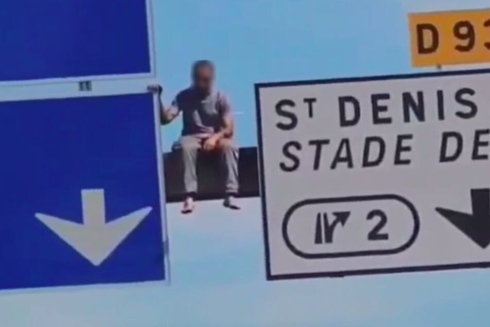 Un homme perché sur un panneau de l'autoroute A1, en région parisienne 