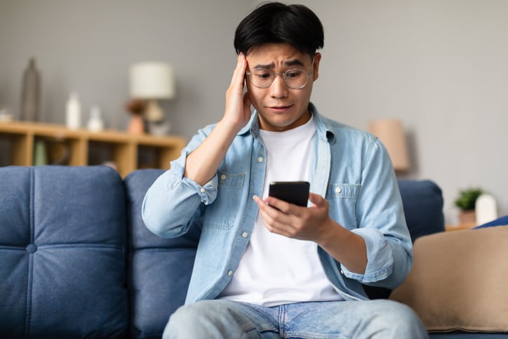 Un jeune homme inquiet devant son smartphone