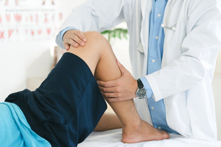 Un médecin examine une douleur à la jambe