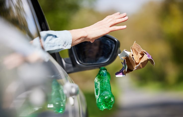 Une personne jette ses déchets par la fenêtre de sa voiture