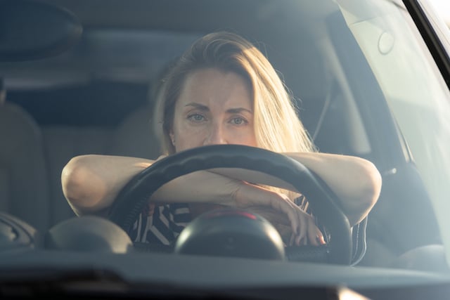 Une femme a l'air pensif dans une voiture