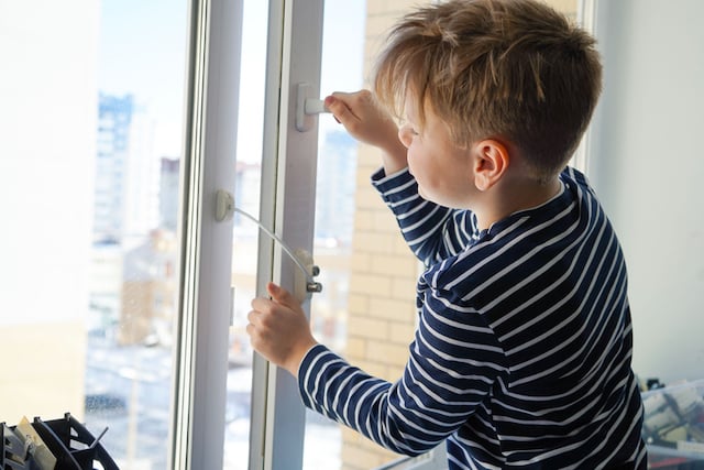 Un petite garçon qui tente d'ouvrir une fenêtre