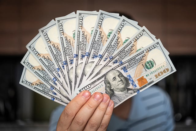 Un homme qui tient des billets de 100 dollars